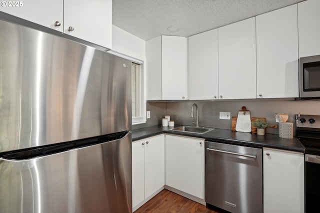 kitchen featuring a textured ceiling, stainless steel appliances, sink, white cabinets, and dark hardwood / wood-style floors