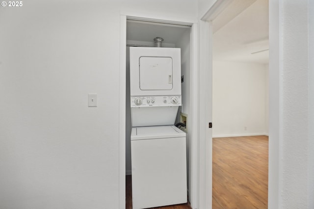 laundry area with ceiling fan, stacked washing maching and dryer, and hardwood / wood-style flooring