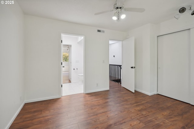 unfurnished bedroom featuring dark hardwood / wood-style flooring, ceiling fan, a closet, and ensuite bathroom