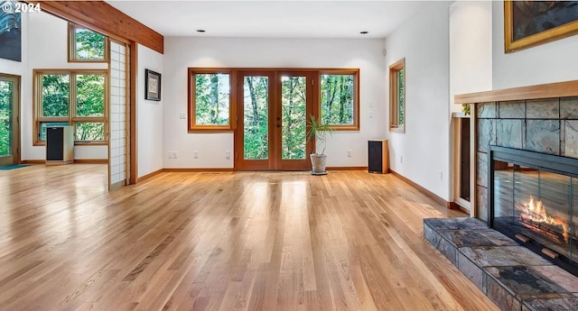 6733 NW Cornell Rd, Portland, OR 97229 - unfurnished living room with a tiled fireplace, light wood-type flooring, baseboards, and french doors