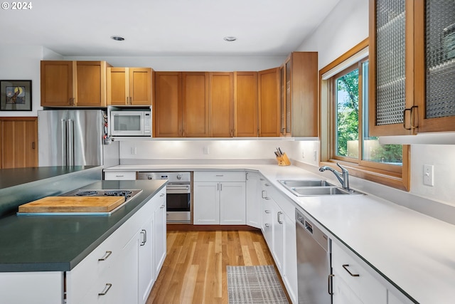 6733 NW Cornell Rd, Portland, OR 97229 - kitchen featuring stainless steel appliances, a sink, light wood-type flooring, glass insert cabinets, and white cabinets