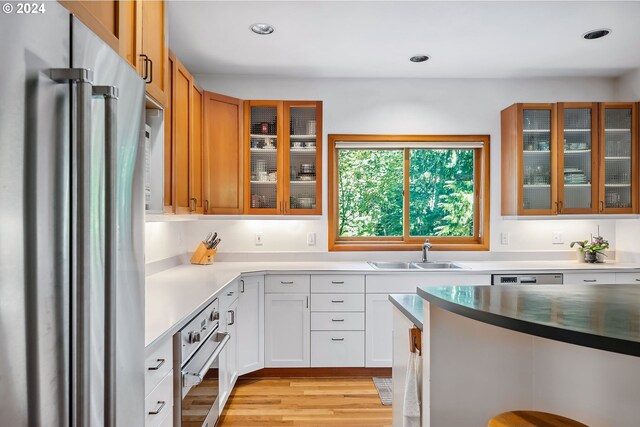 6733 NW Cornell Rd, Portland, OR 97229 - kitchen with stainless steel appliances, a sink, glass insert cabinets, light wood-style flooring, and recessed lighting