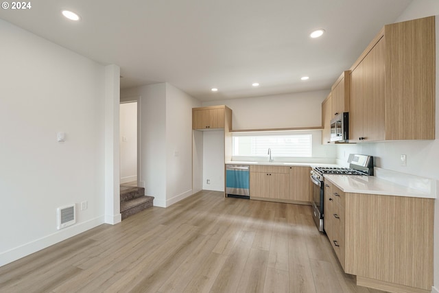 kitchen featuring sink, stainless steel appliances, light brown cabinetry, and light hardwood / wood-style flooring