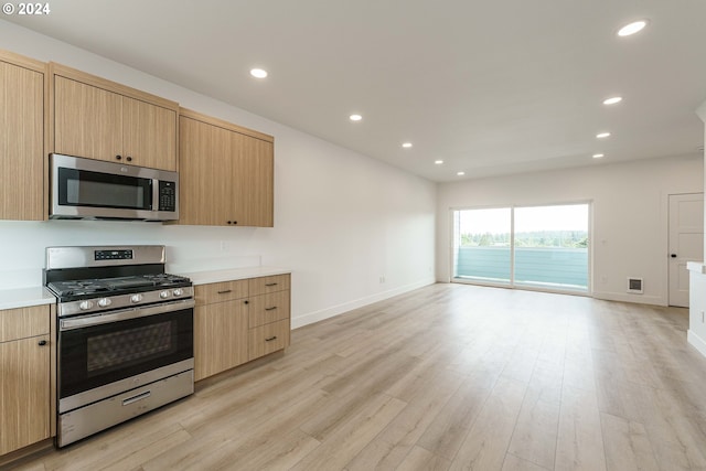 kitchen featuring stainless steel appliances, light brown cabinetry, and light hardwood / wood-style flooring