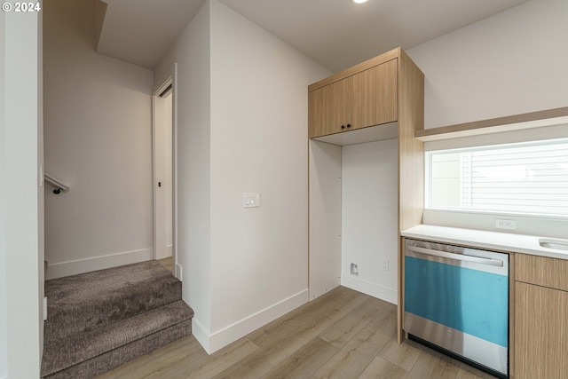 kitchen with light brown cabinetry, stainless steel dishwasher, and light wood-type flooring