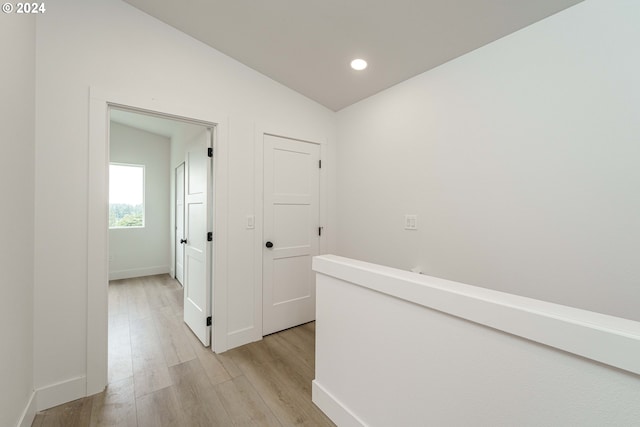 corridor with lofted ceiling and light wood-type flooring