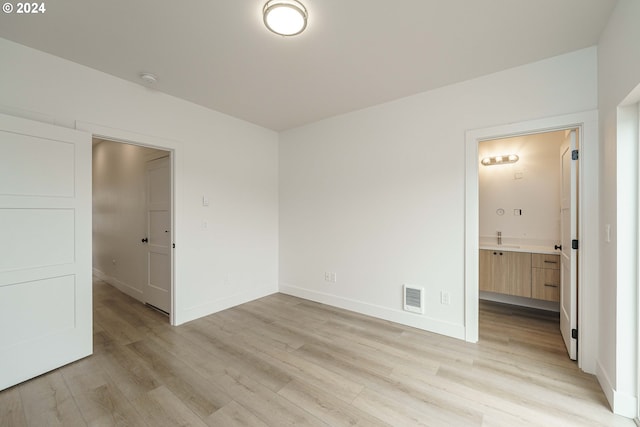 unfurnished bedroom featuring connected bathroom and light hardwood / wood-style flooring