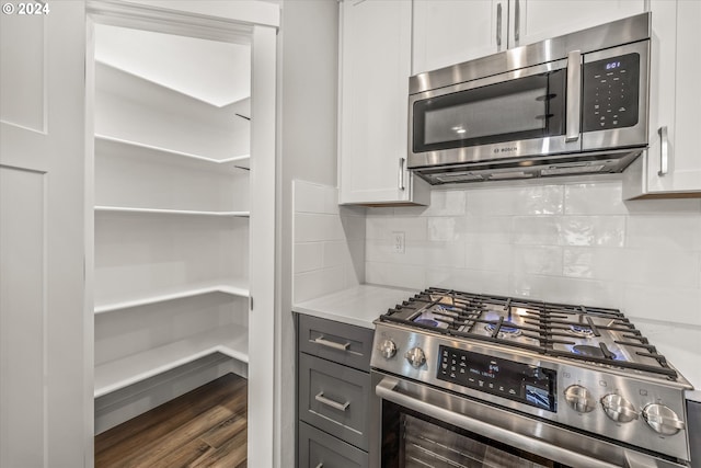 kitchen featuring white cabinetry, light stone counters, dark hardwood / wood-style floors, decorative backsplash, and appliances with stainless steel finishes