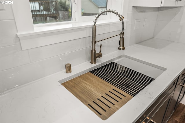 details featuring decorative backsplash, white cabinetry, and sink