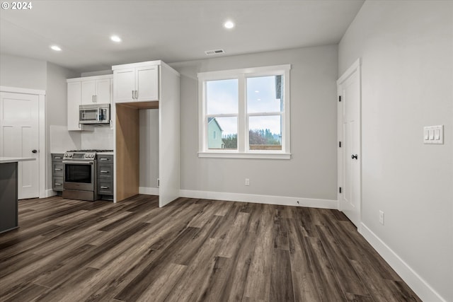 kitchen with dark hardwood / wood-style floors, decorative backsplash, white cabinetry, and appliances with stainless steel finishes