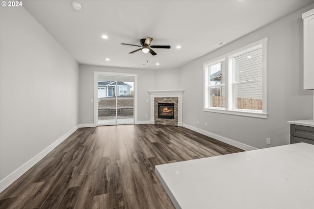 unfurnished living room featuring ceiling fan, dark hardwood / wood-style flooring, and a fireplace