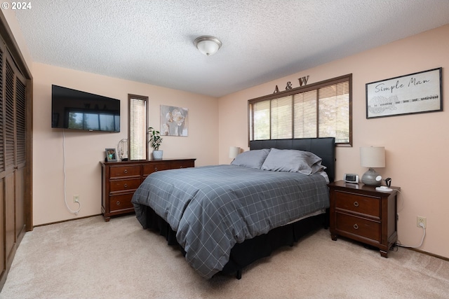 bedroom featuring a closet, light colored carpet, and a textured ceiling