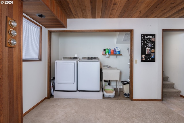 clothes washing area with wooden ceiling, sink, washer and dryer, and light colored carpet