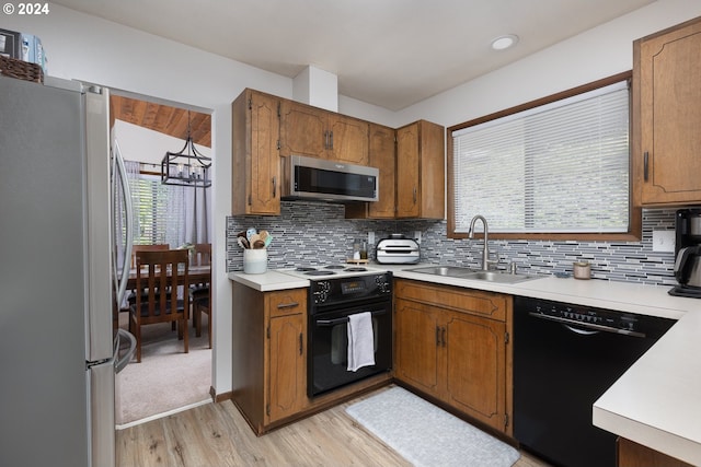 kitchen with decorative backsplash, light wood-type flooring, black appliances, and sink