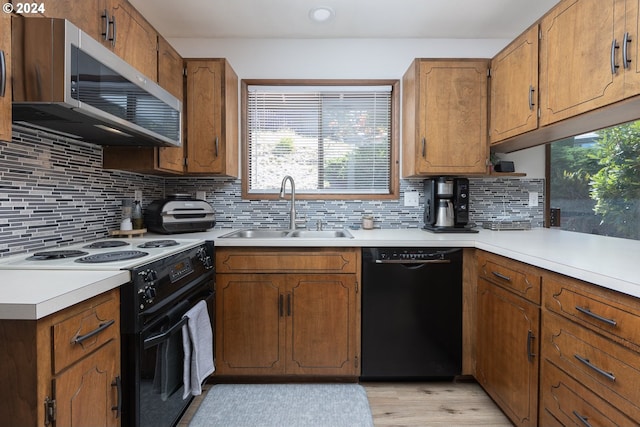 kitchen with decorative backsplash, black appliances, light hardwood / wood-style floors, and sink