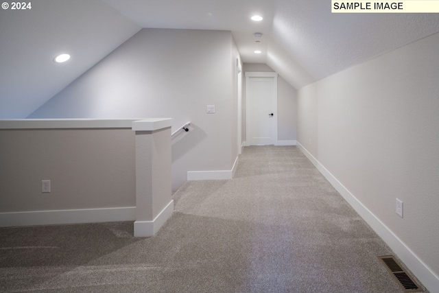 hallway featuring lofted ceiling and light carpet