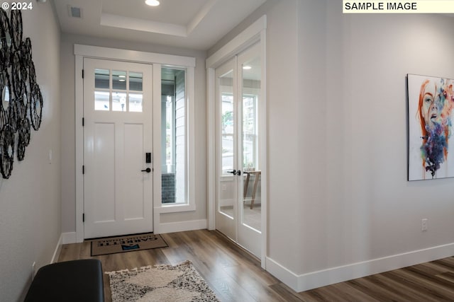 entrance foyer with a tray ceiling, french doors, and light hardwood / wood-style floors