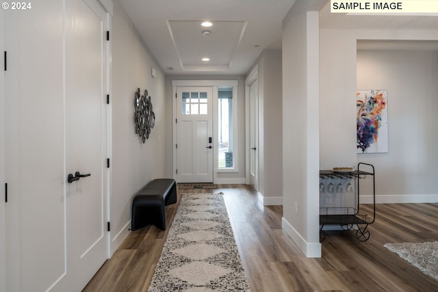 foyer with wood-type flooring and a raised ceiling