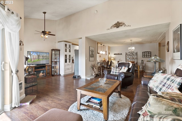 living room featuring ceiling fan, high vaulted ceiling, a textured ceiling, and dark hardwood / wood-style flooring