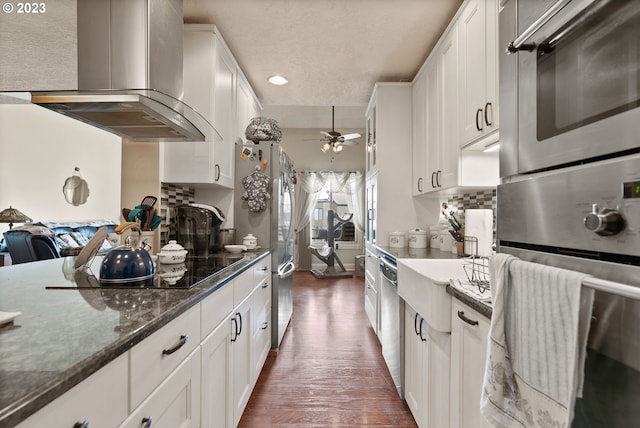 kitchen featuring wall chimney exhaust hood, white cabinets, dark stone countertops, and dark hardwood / wood-style floors