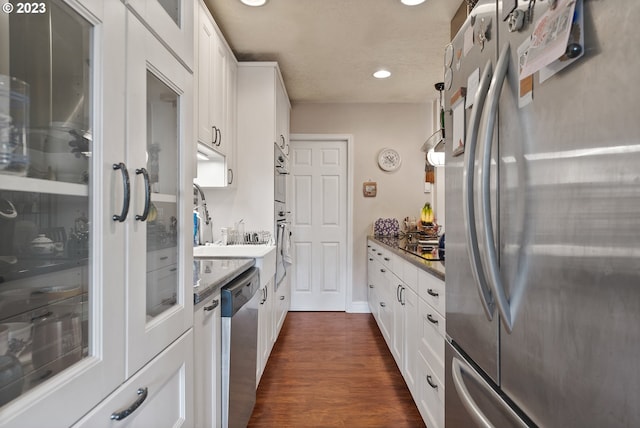 kitchen with dark stone countertops, stainless steel appliances, dark hardwood / wood-style flooring, and white cabinets