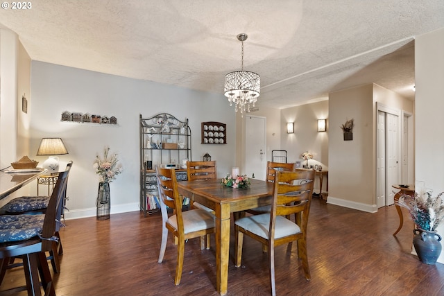 dining area with dark wood-type flooring, a textured ceiling, and an inviting chandelier