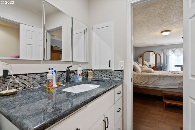 bathroom with vanity, hardwood / wood-style floors, tasteful backsplash, and a textured ceiling