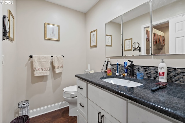 bathroom featuring toilet, decorative backsplash, vanity, and hardwood / wood-style floors