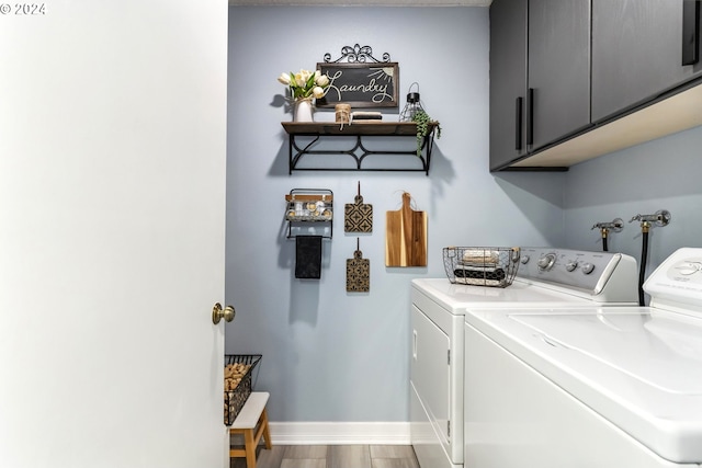 laundry room with washing machine and dryer, wood-type flooring, and cabinets