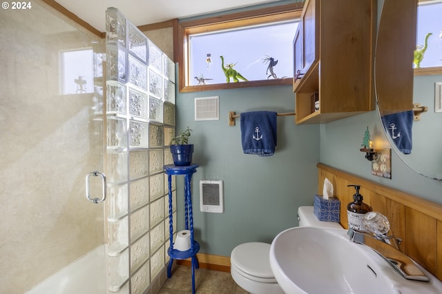 bathroom with sink, a shower with shower door, toilet, and a healthy amount of sunlight