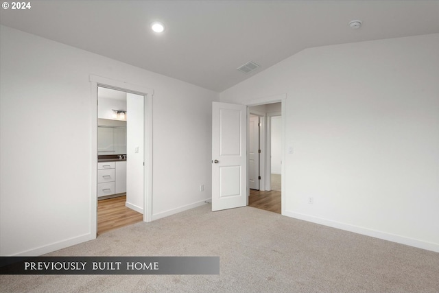 unfurnished bedroom featuring carpet floors, visible vents, vaulted ceiling, and baseboards