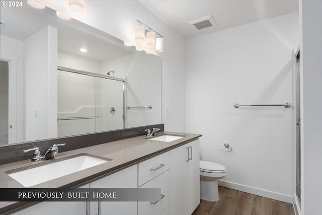 full bath featuring toilet, a shower stall, a sink, and wood finished floors