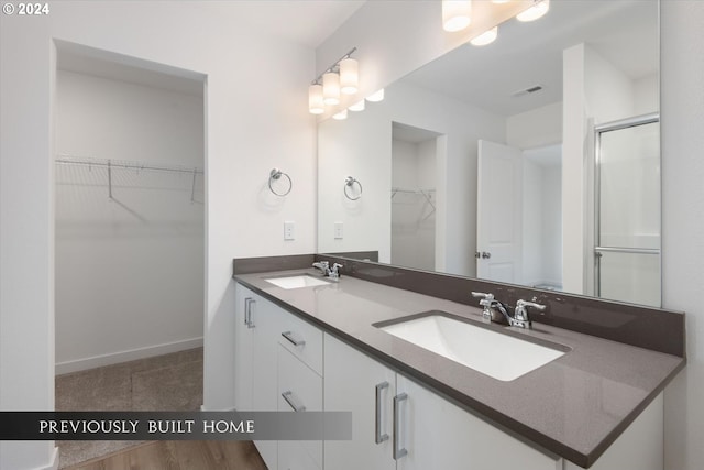 bathroom with double vanity, a spacious closet, a sink, and visible vents