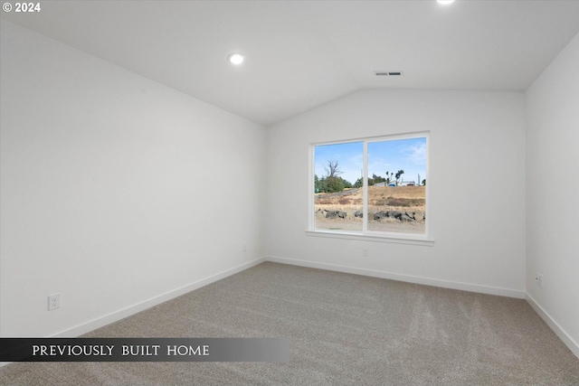 empty room featuring carpet floors, baseboards, visible vents, and vaulted ceiling