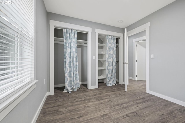 unfurnished bedroom with multiple closets and dark wood-type flooring