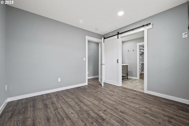 unfurnished bedroom featuring a barn door and light hardwood / wood-style flooring