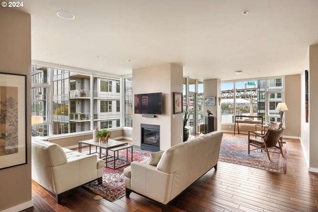 living area featuring baseboards, a glass covered fireplace, and hardwood / wood-style flooring