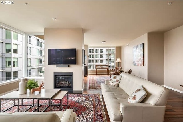 living room featuring a glass covered fireplace, wood finished floors, and baseboards