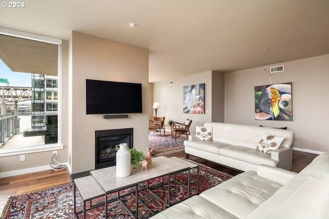 living area with wood finished floors, a fireplace, baseboards, and visible vents