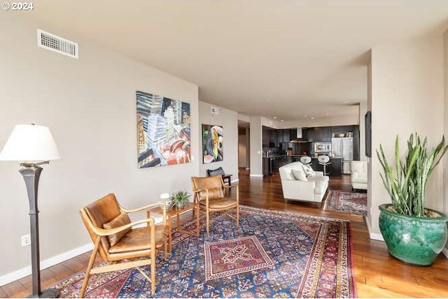 living room featuring visible vents, baseboards, and wood finished floors