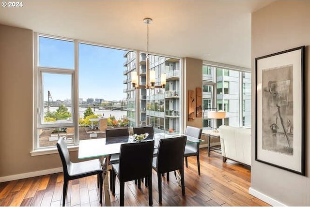 dining room with a city view, hardwood / wood-style floors, floor to ceiling windows, an inviting chandelier, and baseboards