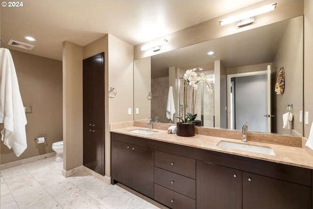 full bathroom with a sink, visible vents, toilet, and double vanity