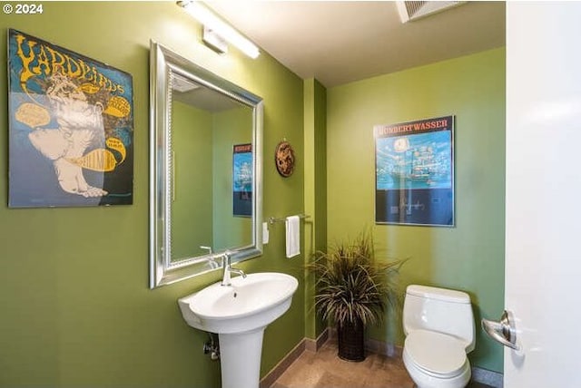 bathroom featuring toilet, baseboards, and a sink