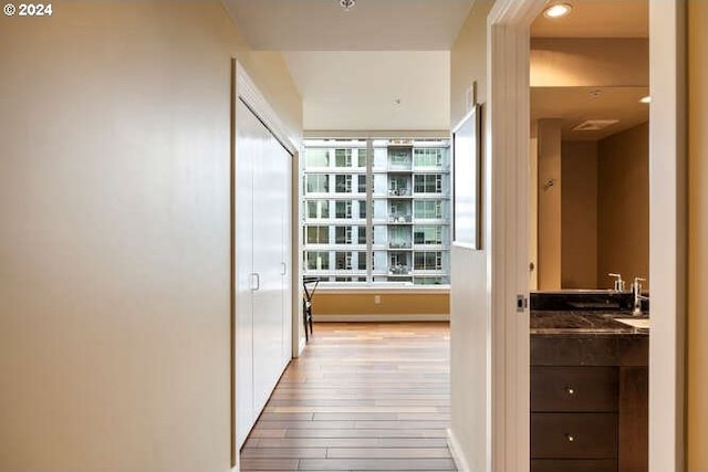 corridor featuring light wood-style flooring and a sink