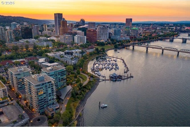 aerial view at dusk featuring a water view and a view of city