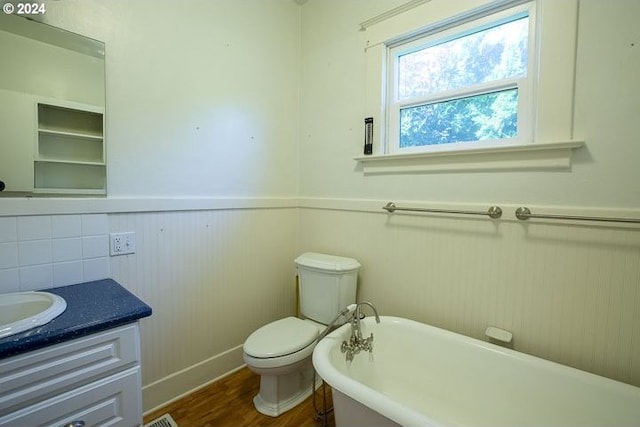 bathroom with toilet, wood-type flooring, vanity, and a bathtub