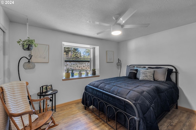 bedroom with hardwood / wood-style floors, ceiling fan, and a textured ceiling