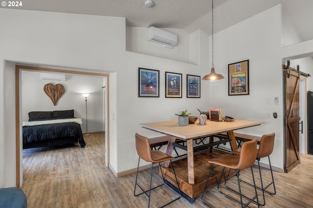 dining area featuring an AC wall unit, a barn door, high vaulted ceiling, and hardwood / wood-style flooring