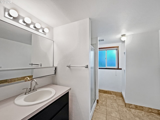 bathroom with vanity, tile patterned floors, a textured ceiling, and a shower with door