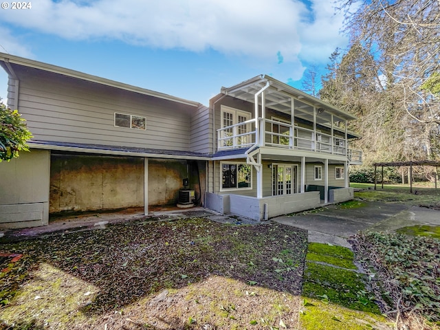 back of property with central air condition unit, a patio, a sunroom, and a balcony